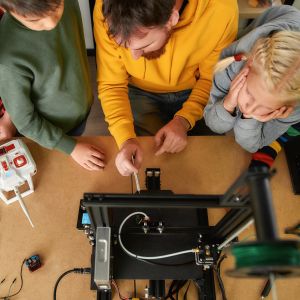 Erwachsener zeigt einem Mädchen und zwei Jungs eine technische Installation
